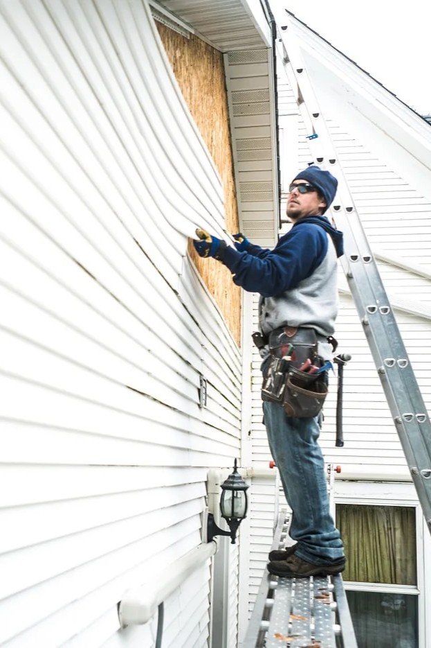 Skilled worker applying cladding to a house — learn more about us and our expert craftsmanship — by Cladding Wellington.