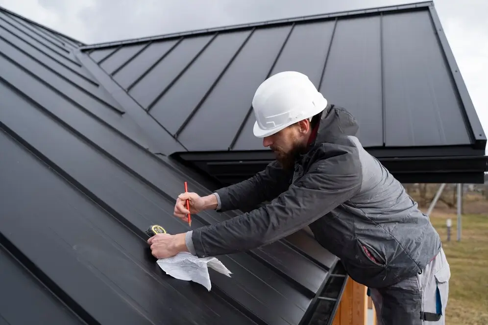 Installer securing exterior cladding near roofline of a contemporary house — by Cladding Wellington.