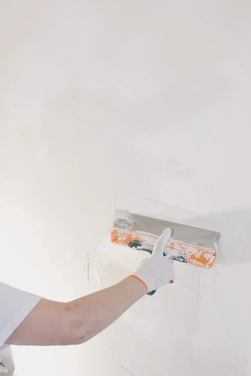 Installer applying plaster cladding to an interior wall, enhancing the space with a sleek and modern look — by Cladding Wellington.