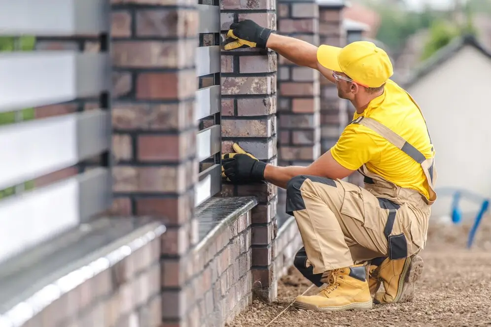 Worker installing stone cladding on a house wall, ensuring a precise and secure fit — by Cladding Wellington.