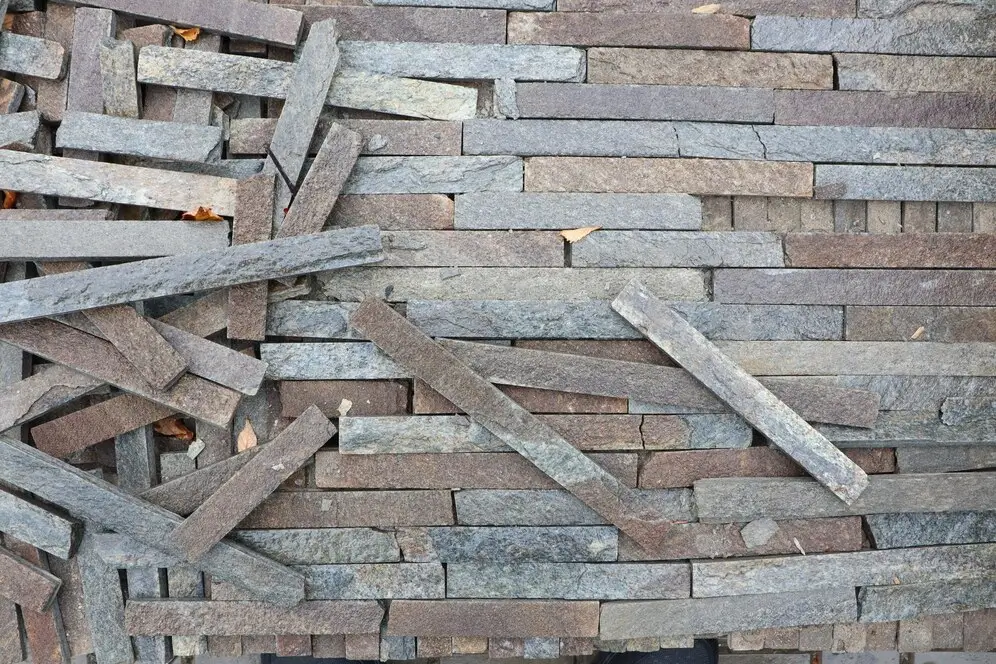 Stones being organized and installed on a house wall, as part of the stone cladding process — by Cladding Wellington.