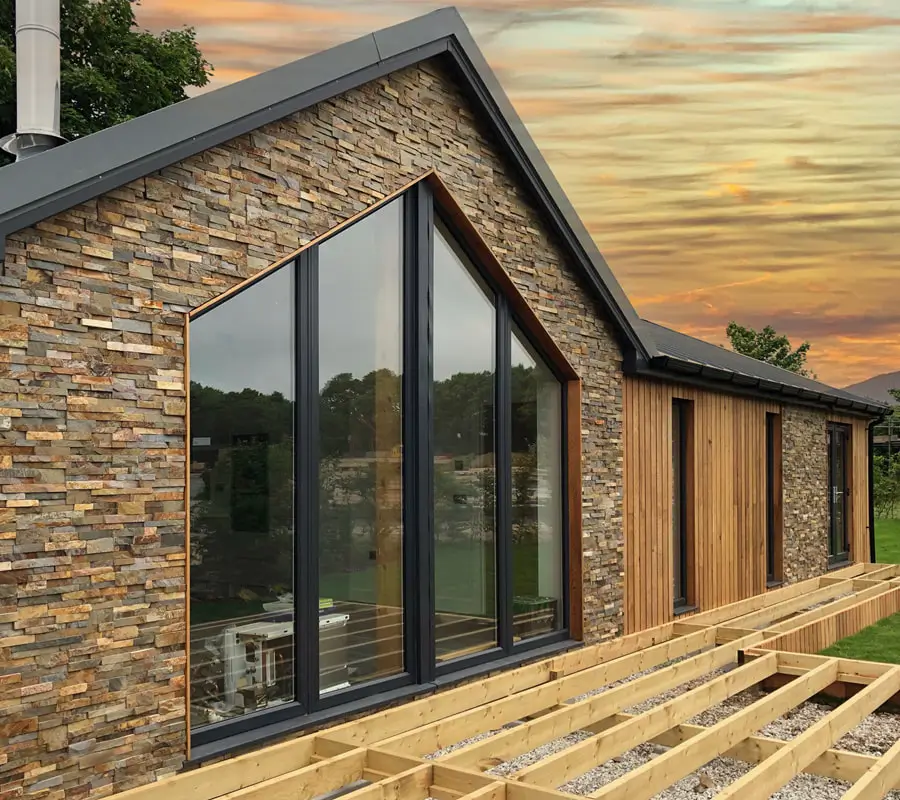 House with stone cladding being installed, transforming the exterior with a natural and stylish finish — by Cladding Wellington.