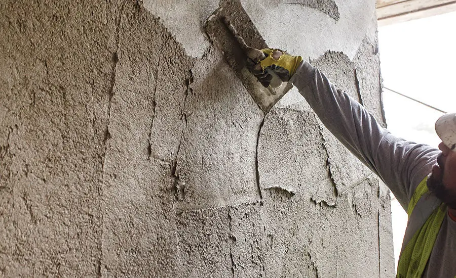 Worker applying stucco cladding to the exterior of a home, creating a textured and weather-resistant finish — by Cladding Wellington.