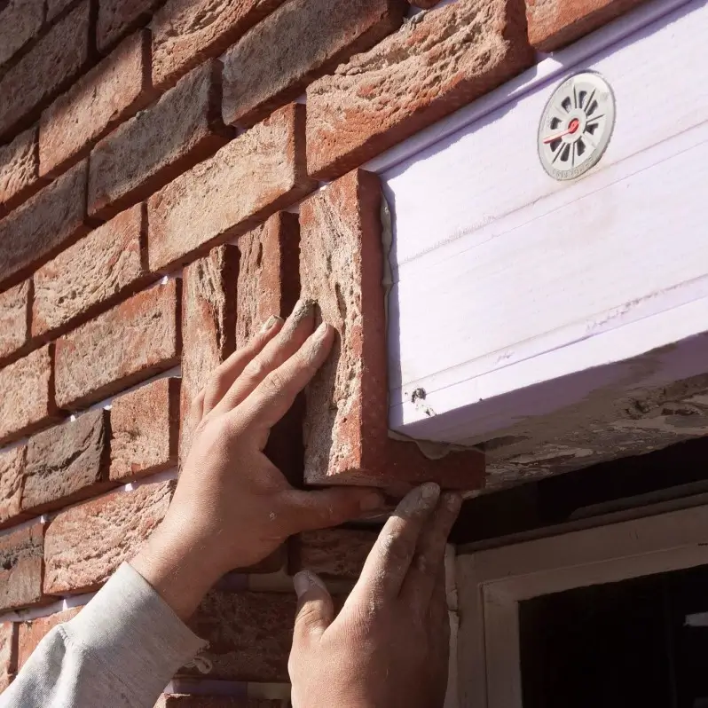 Hands applying exterior brickwork as part of a Cladding Wellington installation