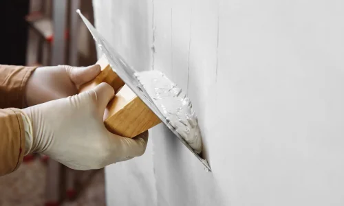 Worker applying plaster cladding to the exterior wall of a house, creating a smooth and durable finish — by Cladding Wellington. Worker applying plaster cladding to the exterior wall of a house, creating a smooth and durable finish — by Cladding Wellington.
